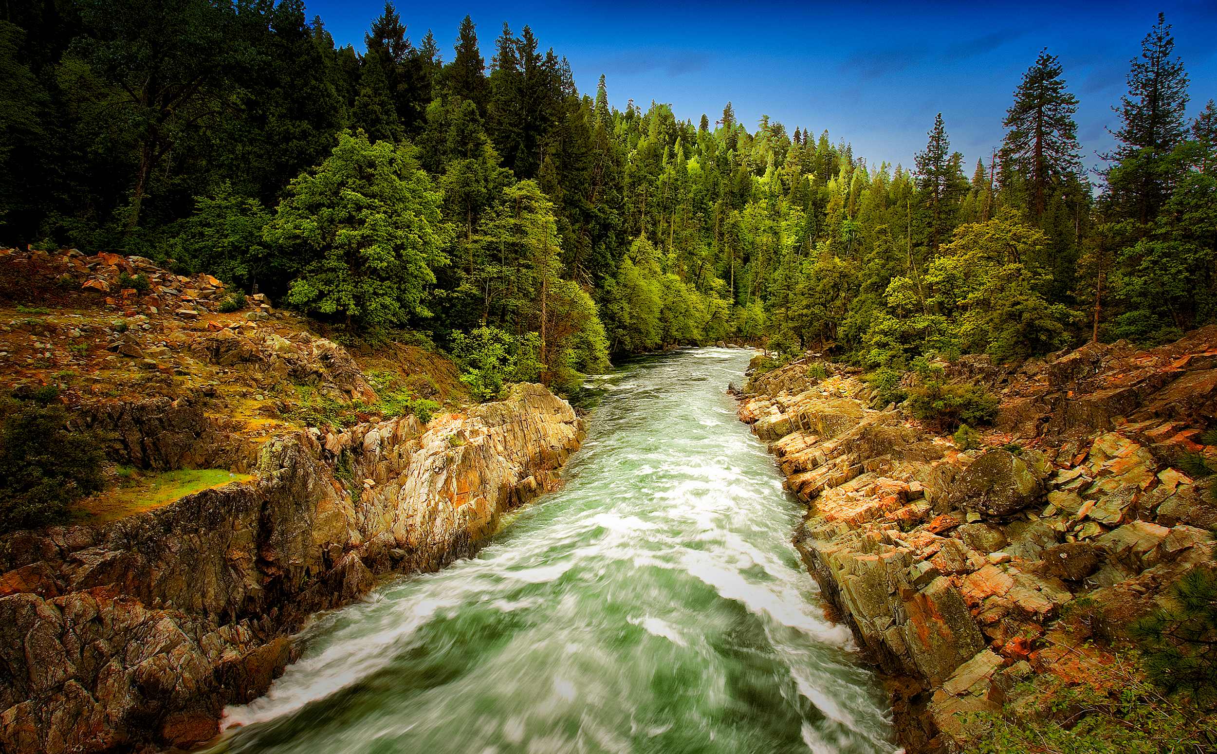Yuba River flowing through a narrow rocky gorge with reddish-orange rocks and dense forest